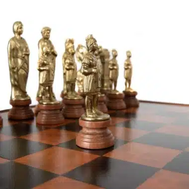 Pièces d'échecs dorées à thème romain alignées en file sur l'échiquier