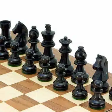 Pièces noires en buis ébonisé alignées sur l'échiquier en noyer, vue rapprochée