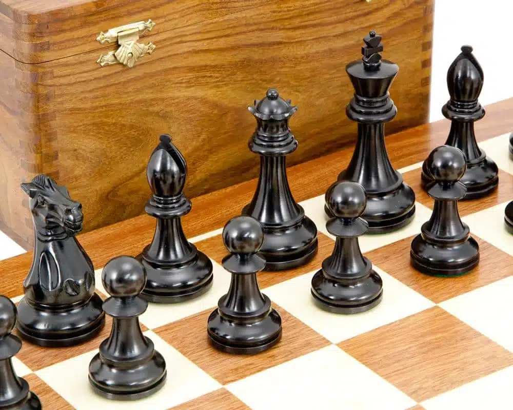 Détail des pièces noires sculptées, roi, dame et pions, sur l'échiquier en bois