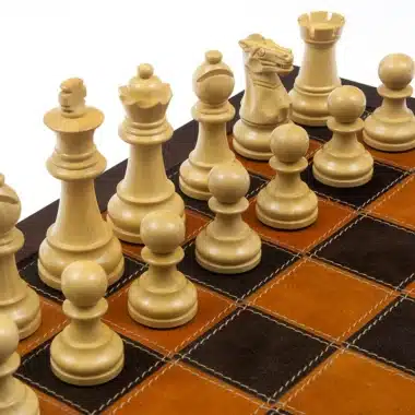 Pièces d'échecs en buis clair disposées sur un échiquier en cuir bicolore