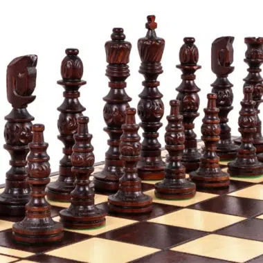 Pièces d'échecs en bois foncé sculpté alignées sur l'échiquier