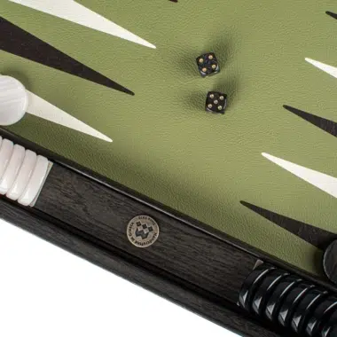 Dés noirs et pion blanc près du médaillon gravé du coffret de backgammon