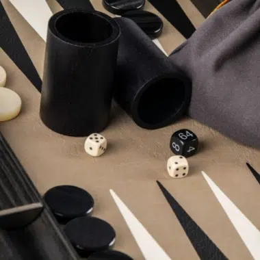 Gobelets à dés en bois et pochon en tissu sur le plateau de backgammon