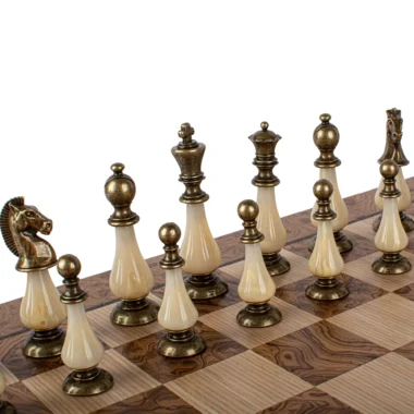 Pièces en laiton et nacre alignées sur l'échiquier en bois de chêne